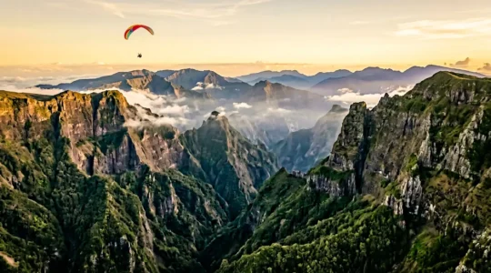 Vue aérienne spectaculaire des cirques volcaniques et remparts vertigineux de La Réunion avec parapentiste en vol