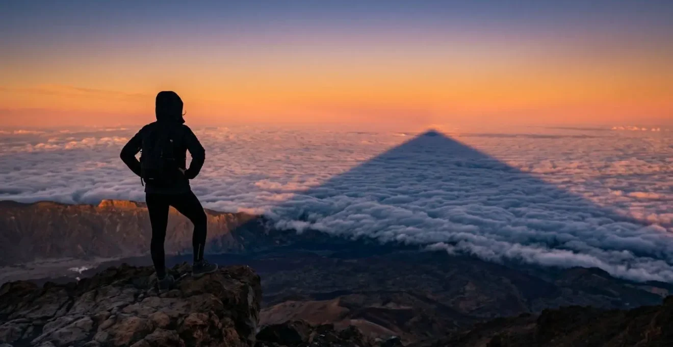 Ombre triangulaire spectaculaire du Piton de la Fournaise projetée sur la mer de nuages au lever du soleil